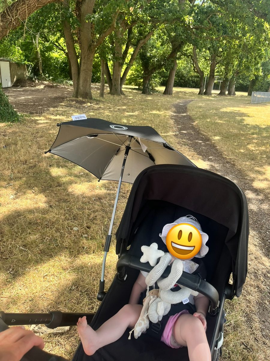 Bugaboo Fox 5 in seat mode on a rough grass and dirt path under trees, with the official Bugaboo umbrella attached